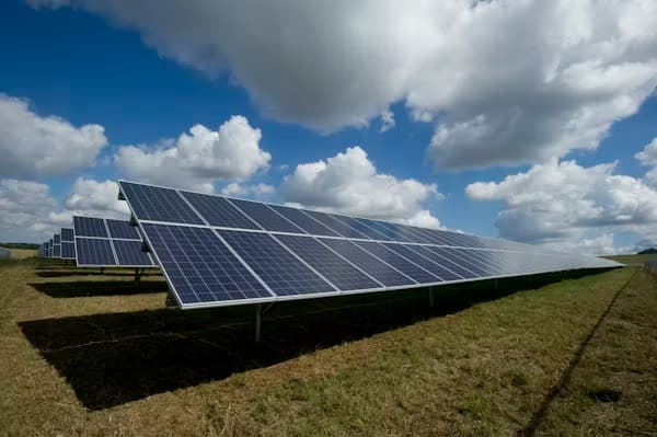 Solar panels in a green field under a bright blue sky